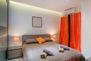 een slaapkamer met een bed, 2 lampen en oranje gordijnen bij La Rive Apartment in Sliema