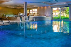Betekints Wellness Hotel في فيسبرم: مسبح بمياه زرقاء في غرفة الفندق