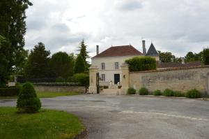 a white house with a brick wall and a driveway at Logis Des Bessons in Migron