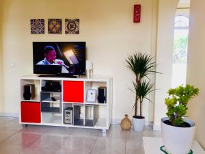 a living room with a tv on a white cabinet at Tavira Garden- One Bedroom with Terrace in Tavira