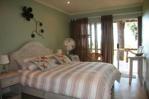 1 dormitorio con 1 cama con edredón blanco en Marula Cottage Guest Lodge, en Thabazimbi