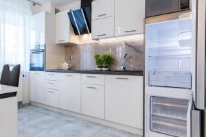 a kitchen with white cabinets and a refrigerator at udanypobyt Apartament Silver Centrum in Zakopane
