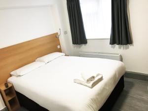 een slaapkamer met een groot wit bed en een raam bij Brentwood Guest House Hotel in Brentwood