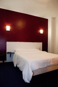a bedroom with a white bed with a red wall at Royal Wagram in Paris