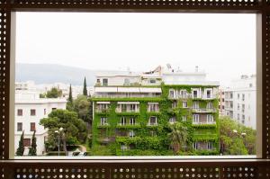 a window view of a building with green ivy at Athinais Hotel in Athens