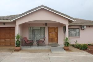 a house with a porch with chairs and a table at Strand Meadows B&B in Gaborone