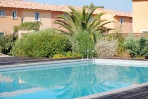 a swimming pool in front of a house with a palm tree at VILLA LES NACRES A 400 MT DAL MARE in Porto-Vecchio