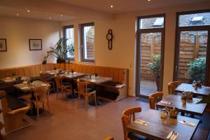 a restaurant with wooden tables and chairs and windows at Pension am Heusteig in Stuttgart