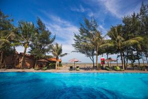 a swimming pool next to a beach with palm trees at Van Chai Resort in Sầm Sơn