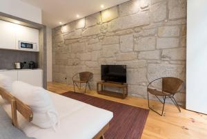 a living room with a stone wall and a tv at LovelyStay - Rico's Apartment - Almada 1ºF in Porto