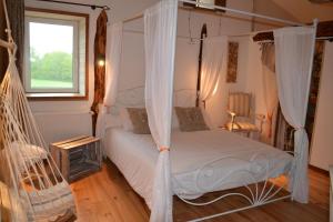 1 dormitorio con cama con dosel y ventana en Le Jardin des Pierres Brunes, en Saint-Jean-des-Ollières