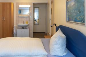 ein Schlafzimmer mit einem Bett und einem Waschbecken mit einem Kissen in der Unterkunft Alfa Apartment Hotel in Neu Isenburg