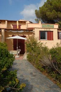 a building with an umbrella and a chair in front of it at Motel Logis d'Abartello in Olmeto