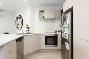 uma cozinha com armários brancos e um frigorífico preto em Stylish and Spacious, Downtown Mount Maunganui em Mount Maunganui