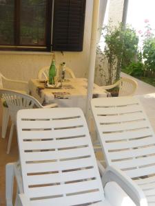 2 chaises blanches assises à côté d'une table et d'une table avec des chaises dans l'établissement Apartment Artusi, à Pula