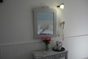 un miroir sur un mur à côté d'une table avec des fleurs dans l'établissement Naiades Almiros Hotel, à Agios Nikolaos