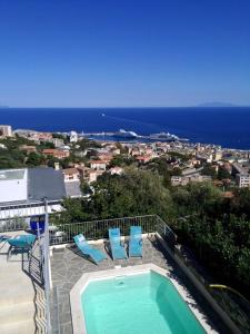 a swimming pool with two blue chairs and the ocean at Villa Patrizia in Bastia