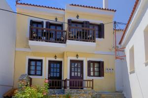 a yellow house with windows and balconies with dogs on them at Achinos Apartments and Maisonettes in Kokkari
