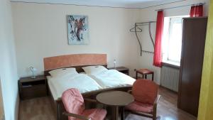 una camera da letto con un letto, un tavolo e delle sedie di Pension "Zum Schwan" a Muhr amSee