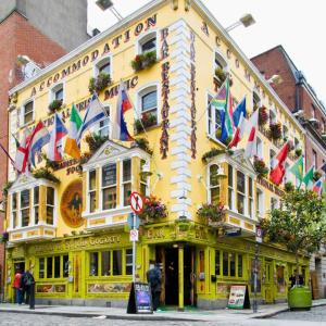 ein gelbes Gebäude mit Flaggen auf der Vorderseite in der Unterkunft Gogartys Temple Bar Hostel in Dublin