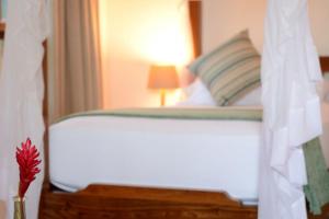 a bedroom with a white bed and a vase with a flower at Kisiwa on the Beach in Paje