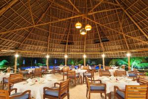 
a dining area with tables and chairs and umbrellas at Kisiwa on the Beach in Paje
