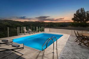 a swimming pool on a patio with a table and chairs at Villa Piedra in Manoliópoulon