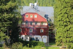 a red and white house with a balcony at Hotel Lesní Chata in Kořenov