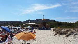 a beach with umbrellas and people on the sand at Villa Eden Home Holiday in Santa Margherita di Pula