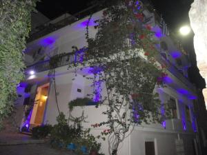 a white building with purple lights on it at Apergis Rooms in Ermoupoli