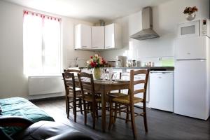 La cuisine est équipée d'une table, de chaises et d'un réfrigérateur blanc. dans l'établissement gite-civray-de-touraine Maison de Denise, à Civray-de-Touraine