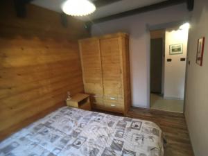 1 dormitorio con 1 cama y pared de madera en Il Capriolo, en Sauze dʼOulx