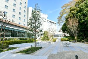 a park with tables and chairs in front of a building at Narita Tobu Hotel Airport in Narita
