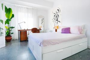 a white bedroom with a bed and a desk at Beach and the City Apartment in Málaga