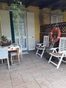 a patio with white chairs and a table and chairs at Appartamenti Claudia Rio in Rio Marina