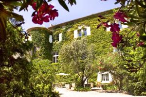 a building covered in green ivy with trees and flowers at Hôtel Château de Cavanac in Carcassonne