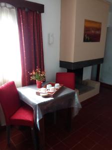 a table with two red chairs and a fireplace at La Casa de Reyes Posada in Reyes