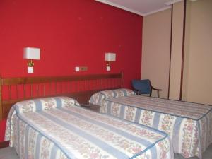 a hotel room with three beds and a red wall at Casa Pardo in Gibaja