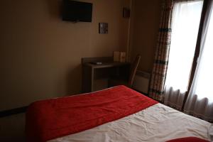 Cette chambre comprend un lit avec une couverture rouge et un bureau. dans l'établissement Hôtel l'Edelweiss, à Châtel