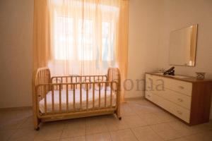 a bedroom with a crib and a dresser and a window at La Posidonia in Donnalucata +9 photos