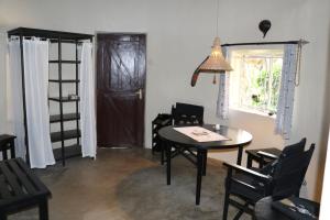 um quarto com uma mesa e cadeiras e uma porta em Nyati Hill Cottages em Nairobi