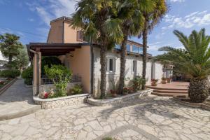 a house with palm trees in front of it at Apartments Kori in Funtana