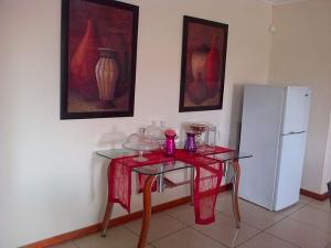 um quarto com uma mesa e um frigorífico branco em Comfort Palace Guesthouse em Francistown
