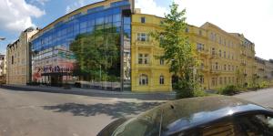 ein gelbes Gebäude mit Glasfassade auf einer Straße in der Unterkunft Grandhotel Nabokov in Marienbad