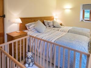 a bedroom with a crib and a teddy bear at Pear Tree Cottages in Wedmore