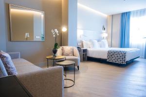 a hotel room with a bed and a couch at Hotel América Sevilla in Seville