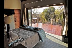 ein Schlafzimmer mit einem Bett und einem großen Fenster in der Unterkunft Feeskraal Lodge in Moheme