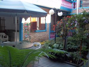 eine Terrasse mit einem Tisch, einem blauen Regenschirm und Pflanzen in der Unterkunft Pousada Riacho Doce in Caraguatatuba