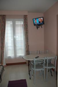 a dining room with a table and a tv on the wall at Residence De La Tour Paris-Malakoff in Malakoff