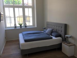 a bedroom with a bed with blue sheets and two windows at Anker Guest House in Bielefeld